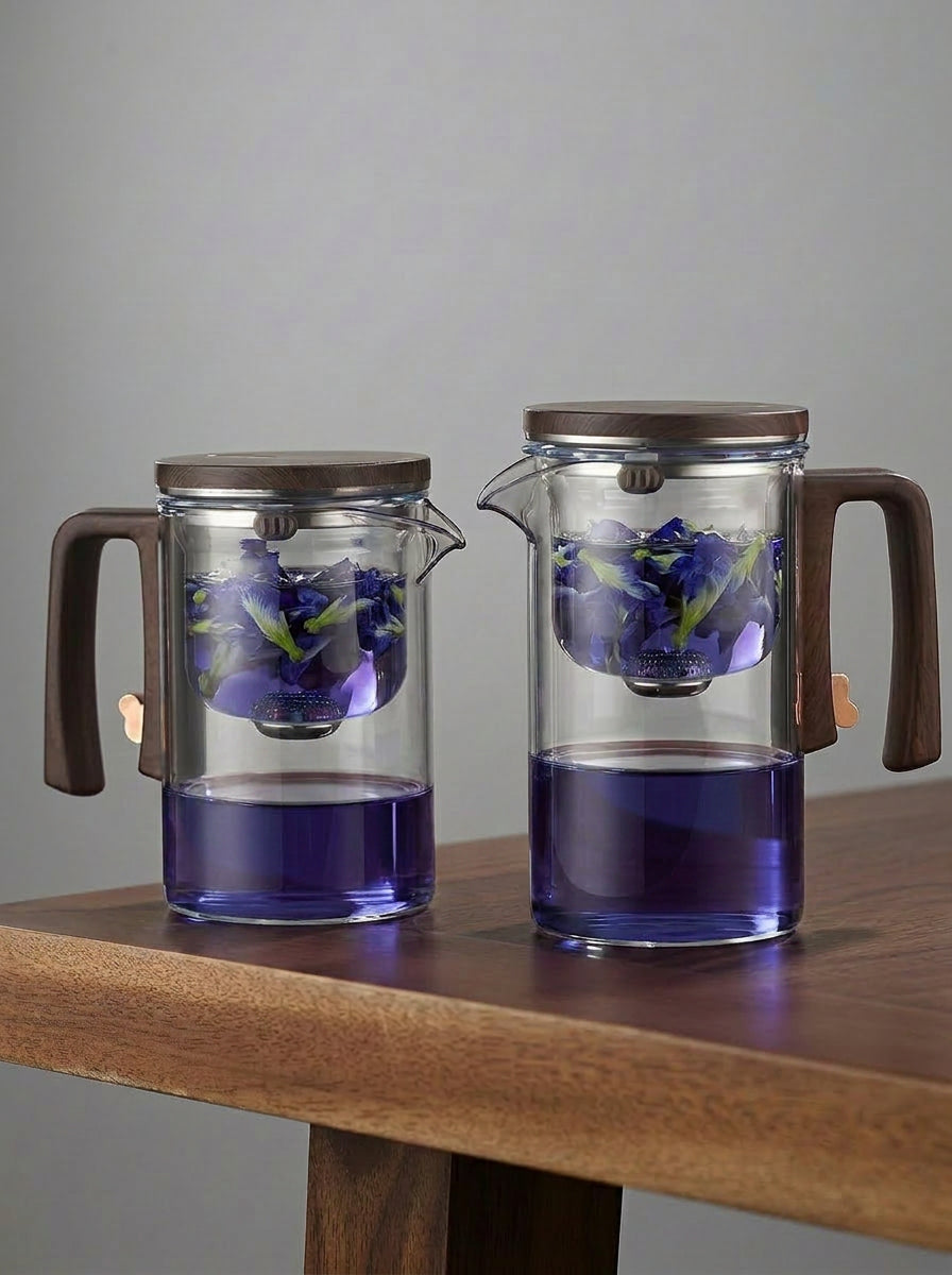 Two glass tea infusers with butterfly pea tea on a walnut table