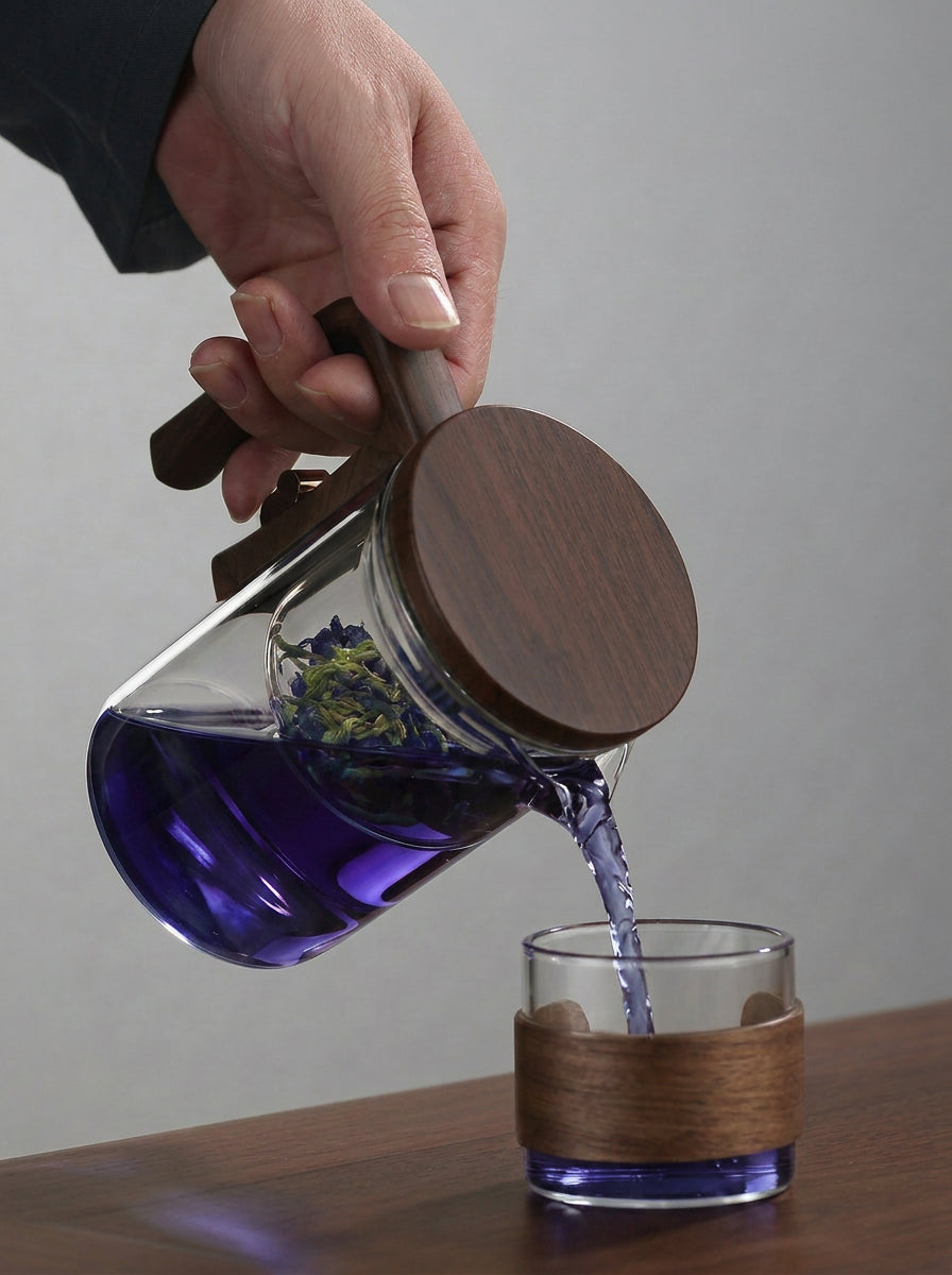 Pouring butterfly pea blue tea from glass infuser